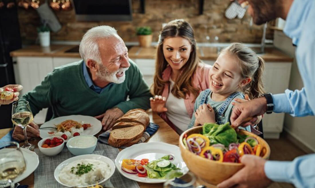 Vesela družina za obloženo mizo s hrano in Acidophilus plus