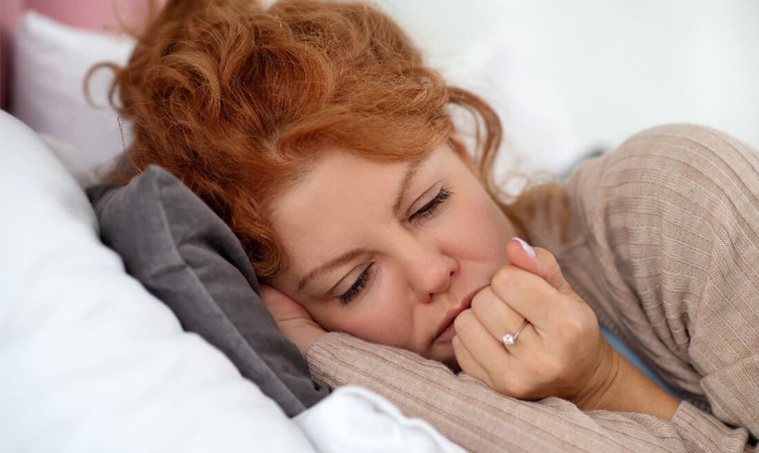 Utrujena ženska spi v postelji