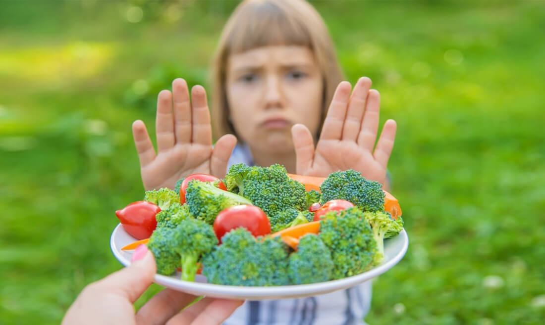 Otrok zavrača krožnik z zelenjavo