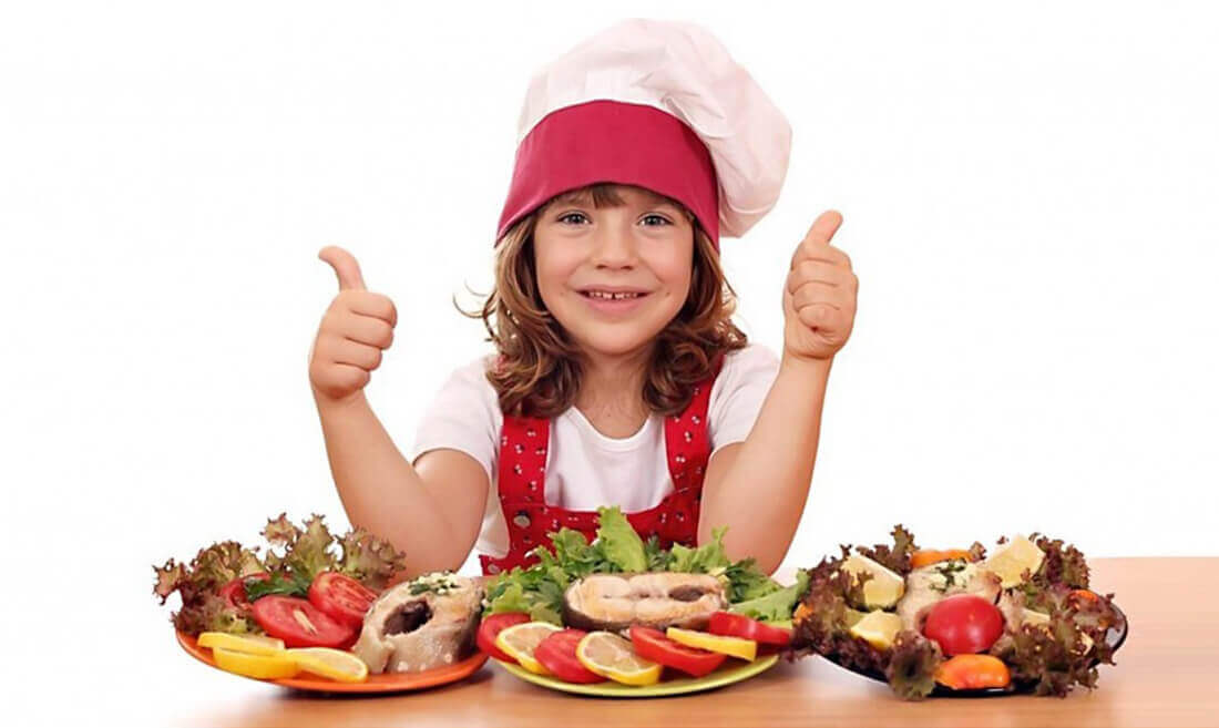 Vesela deklica in miza z ribani in omega-3 za otroke